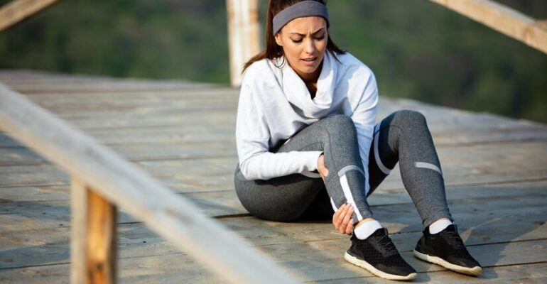 young-sportswoman-experiencing-pain-her-leg-while-having-sports-training-nature_637285-3823