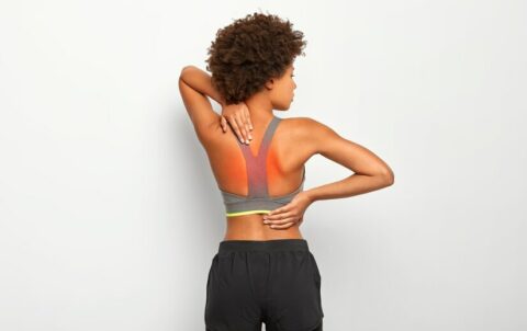 slim-woman-has-cronic-painful-feelings-back-poses-against-white-background-has-injury-cramps-wears-grey-top-shorts_273609-33744