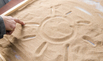 a man draws by his  finger on the sand symbol of the sun