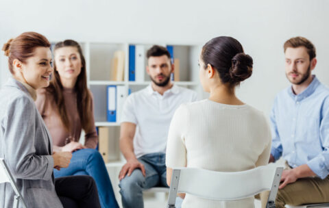 group of people sitting in circle on chairs during support group session