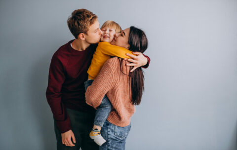 Young family with little son together on grey background