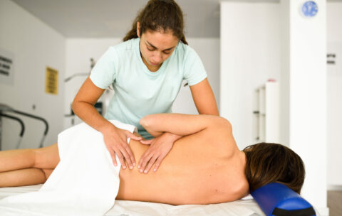 Professional female physiotherapist giving lumbar shoulder massa