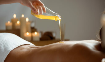 Honey pouring on girl's naked back in spa salon.