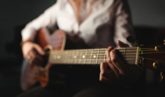 Mid-section of woman playing a guitar in music school
