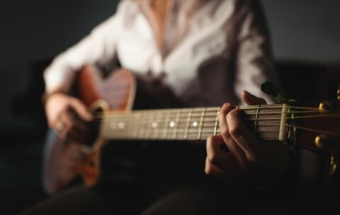 Mid-section of woman playing a guitar in music school
