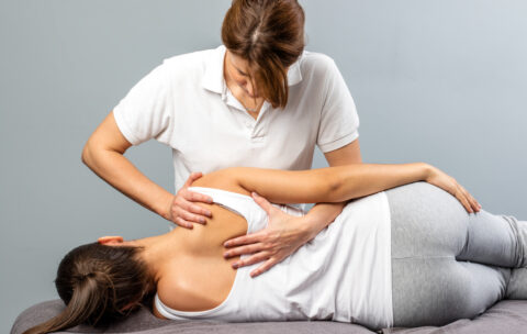 Female therapist manipulating shoulder blade on young female patient.